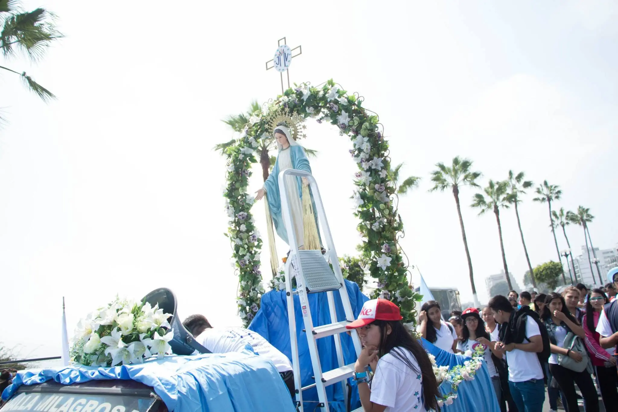Fieles decorando con flores la estatua de la Virgen en una carroza procesional