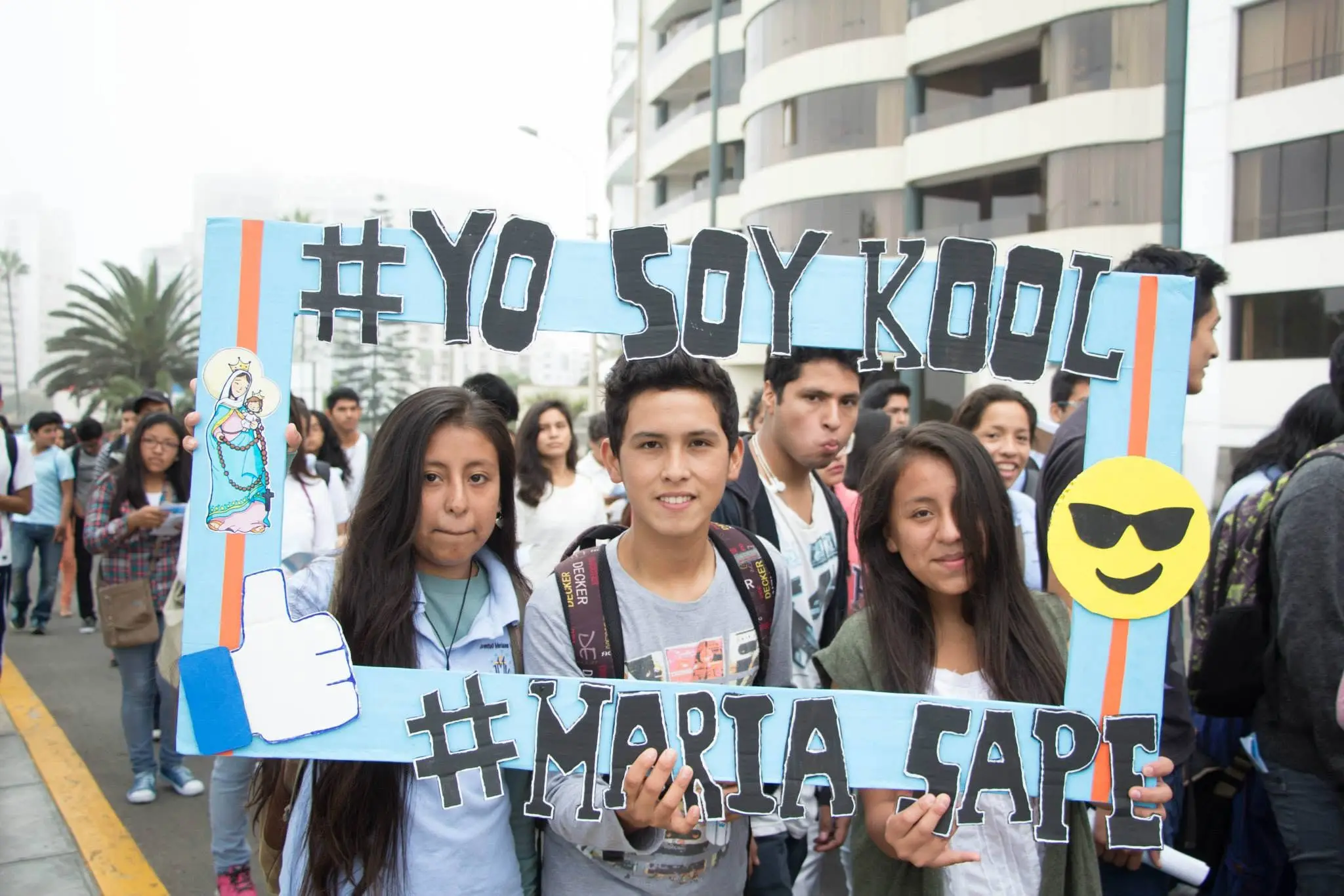 Jóvenes sonrientes posando con un marco de cartón durante la marcha