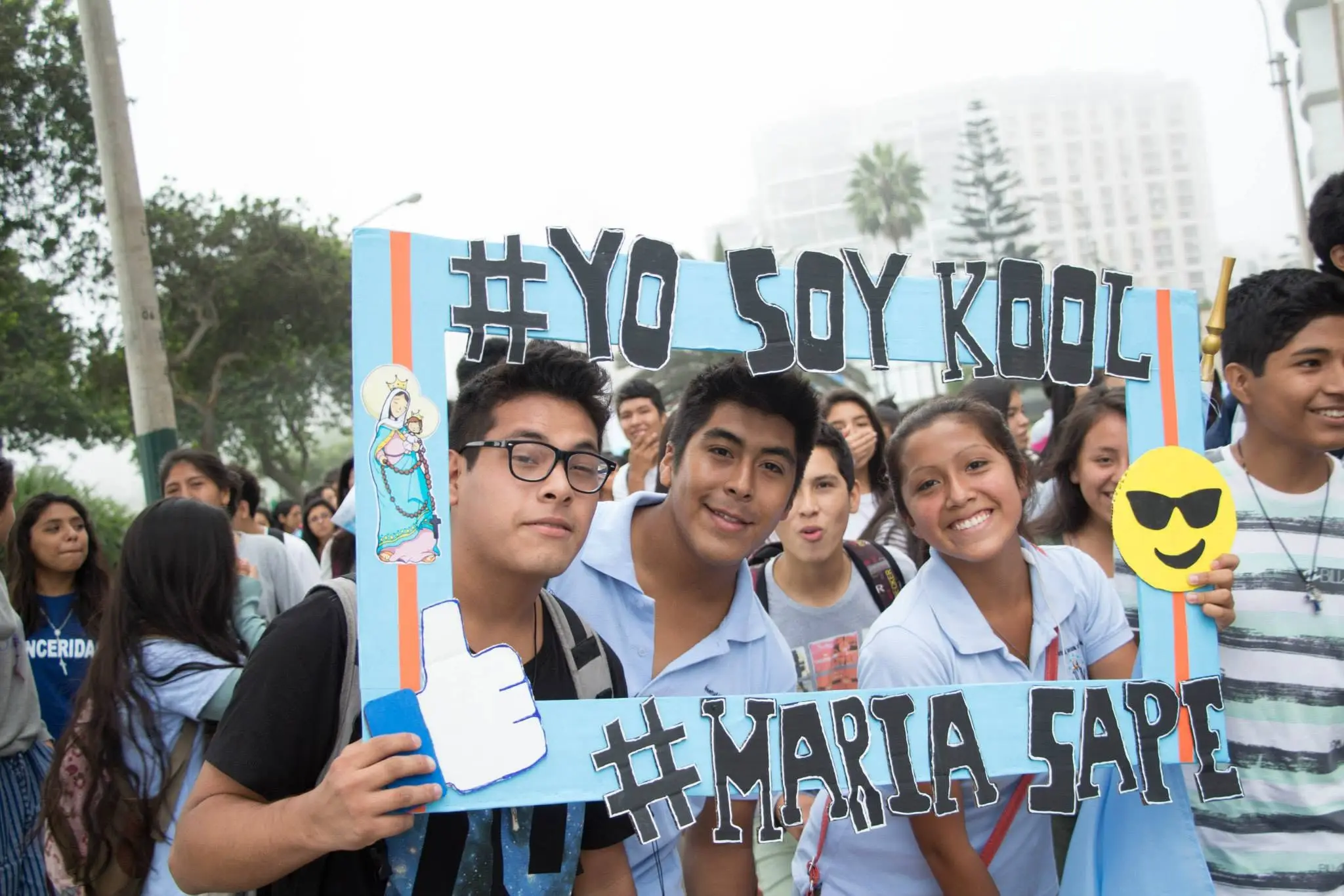 Tres jóvenes posando con un marco de cartón en la marcha