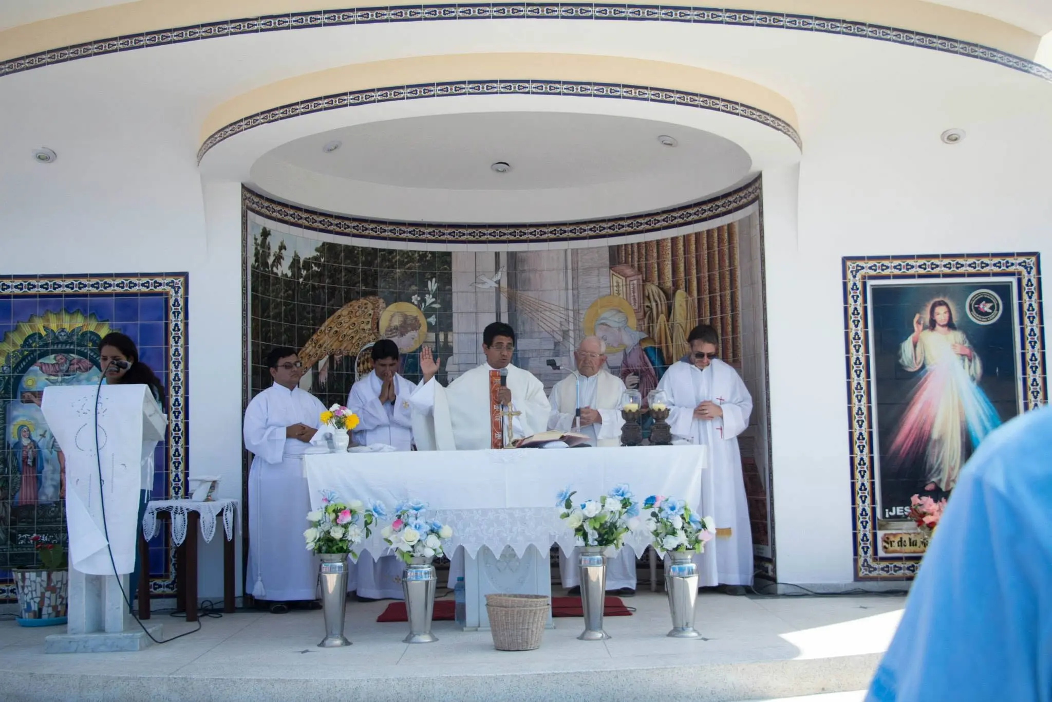 Sacerdotes concelebrando la misa en el altar de una iglesia con retablo de mosaicos