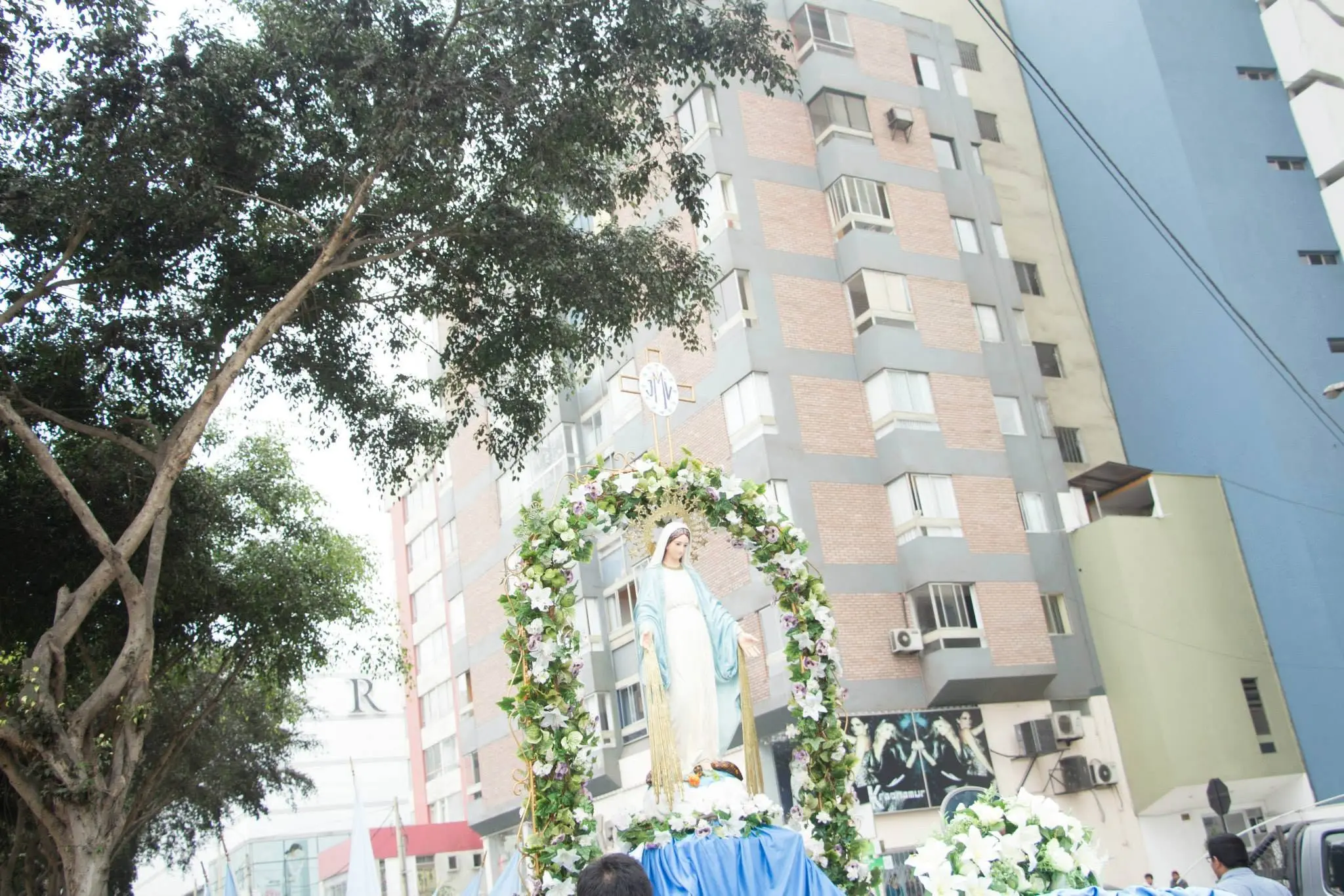 Estatua de la Virgen María sobre una anda decorada con flores en la calle